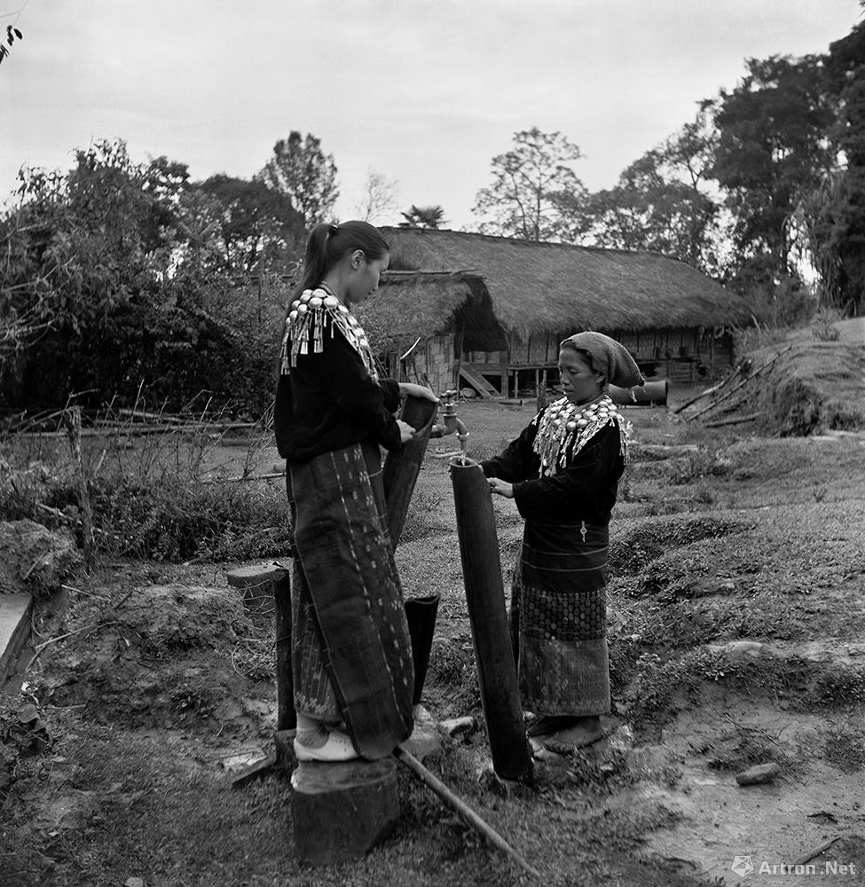 两名景颇族妇女正在用竹筒接自来水