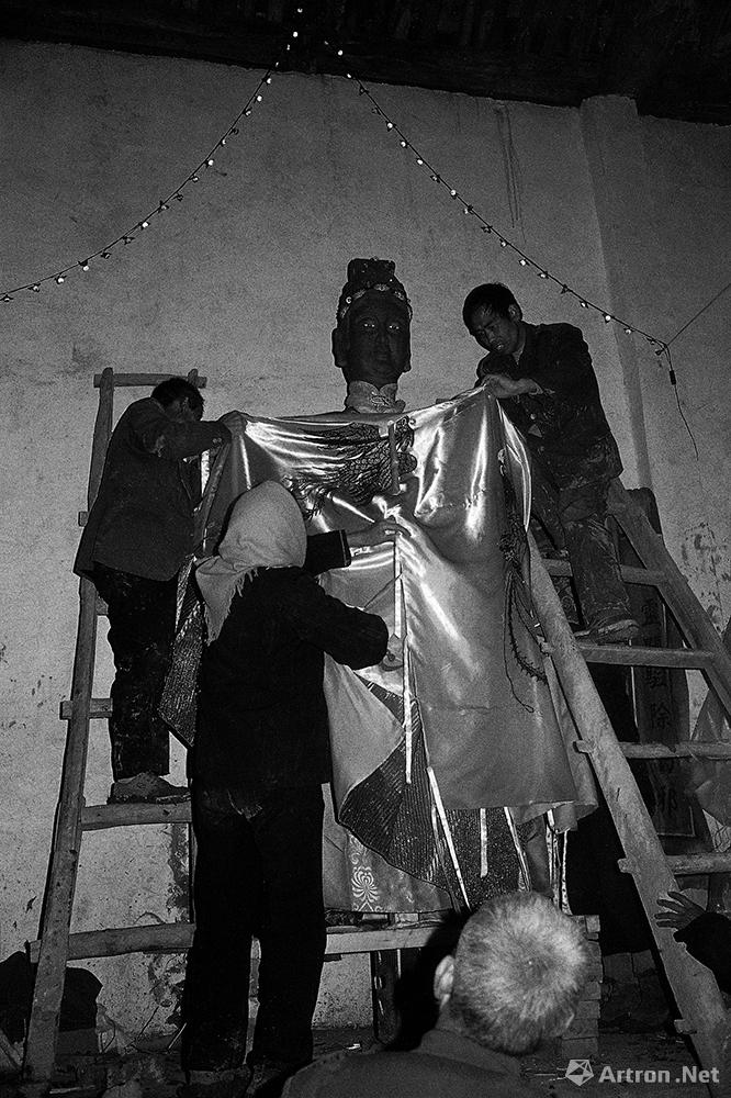 村民们正在庙里为塑造好的神像披挂龙袍