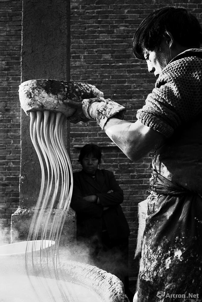 王立力作品：村民朱长安正在用传统的方法漏红薯粉条