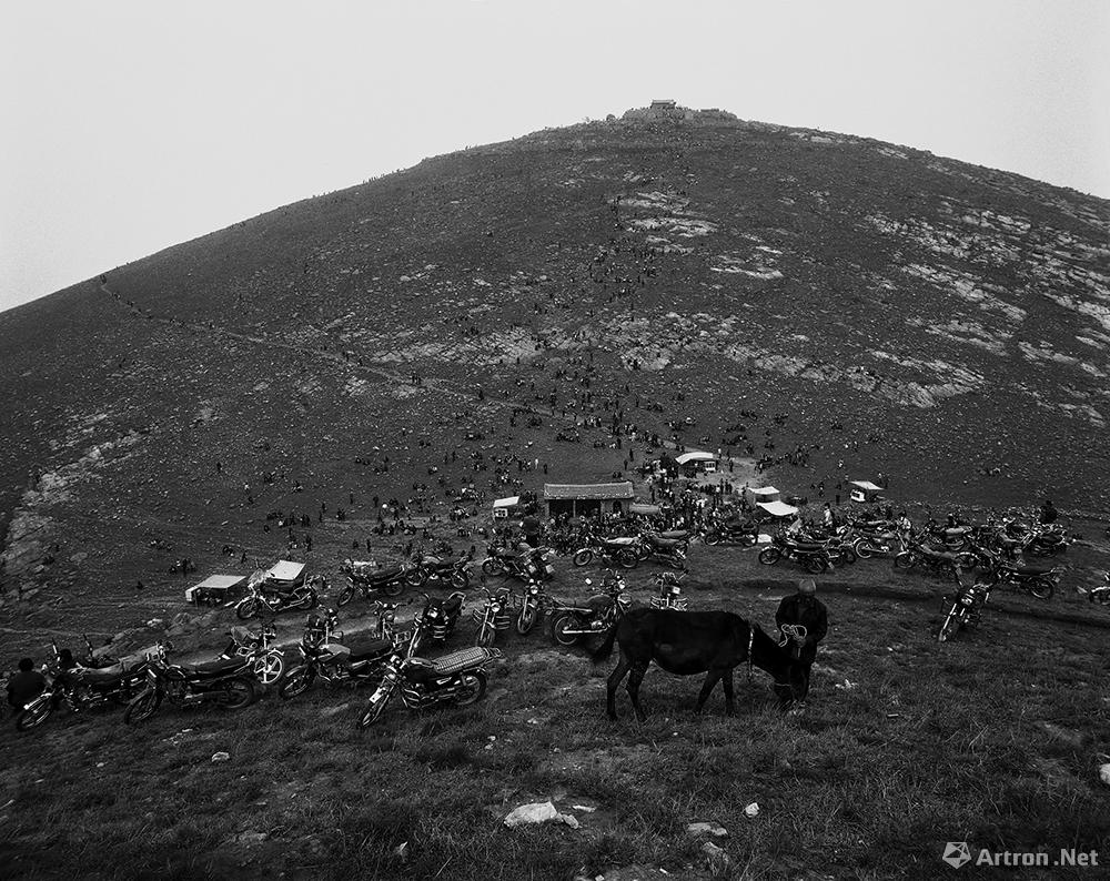 王立力作品：一位村民在停满摩托车的山坡上放马