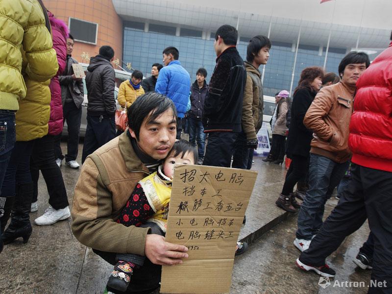 郭斌作品：2012年2月14日，一名父亲抱着小孩在大唐劳务市场招工。